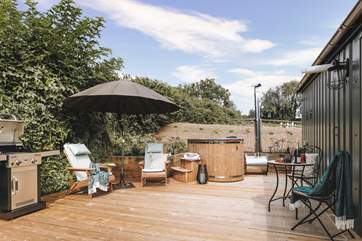The sun soaked deck hosts a dreamy wood-fired hot tub, bistro table, wooden loungers and an impressive barbecue.
