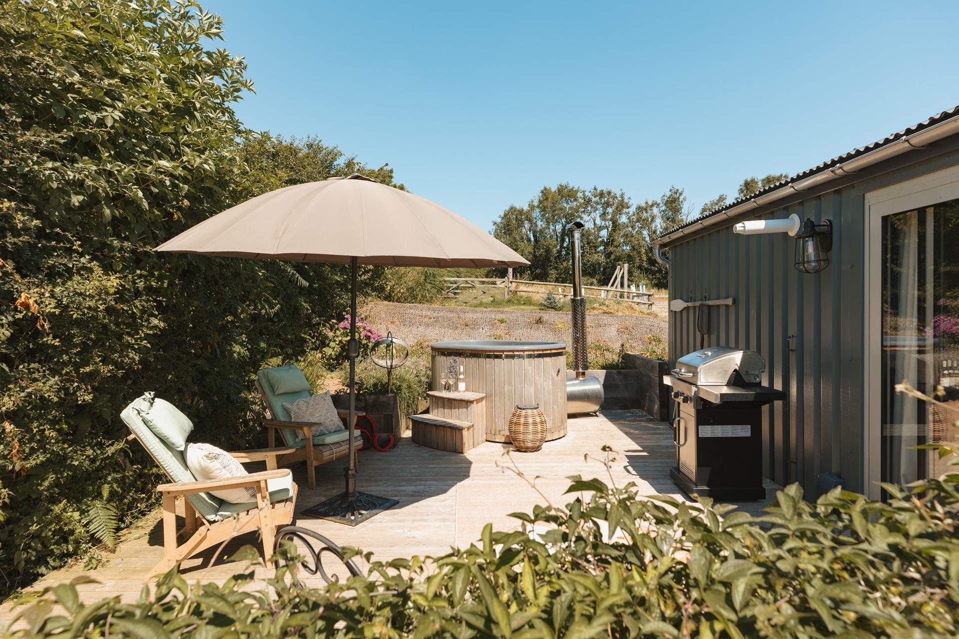 The sun soaked deck hosts a dreamy wood-fired hot tub, bistro table, wooden loungers and an impressive barbecue. 