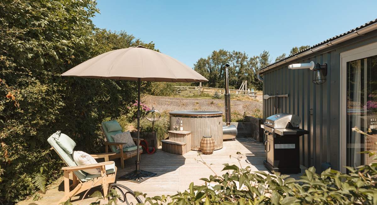 The sun soaked deck hosts a dreamy wood-fired hot tub, bistro table, wooden loungers and an impressive barbecue. 