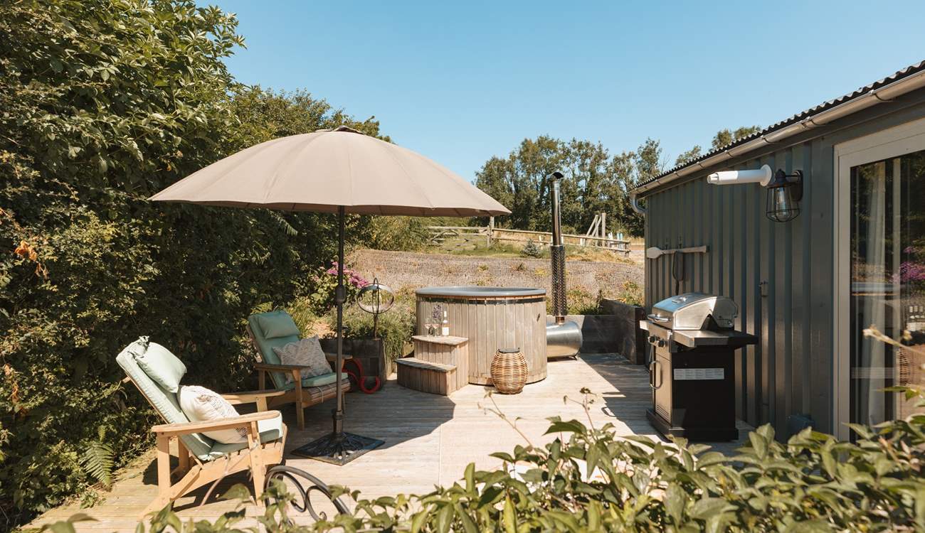 The sun soaked deck hosts a dreamy wood-fired hot tub, bistro table, wooden loungers and an impressive barbecue. 