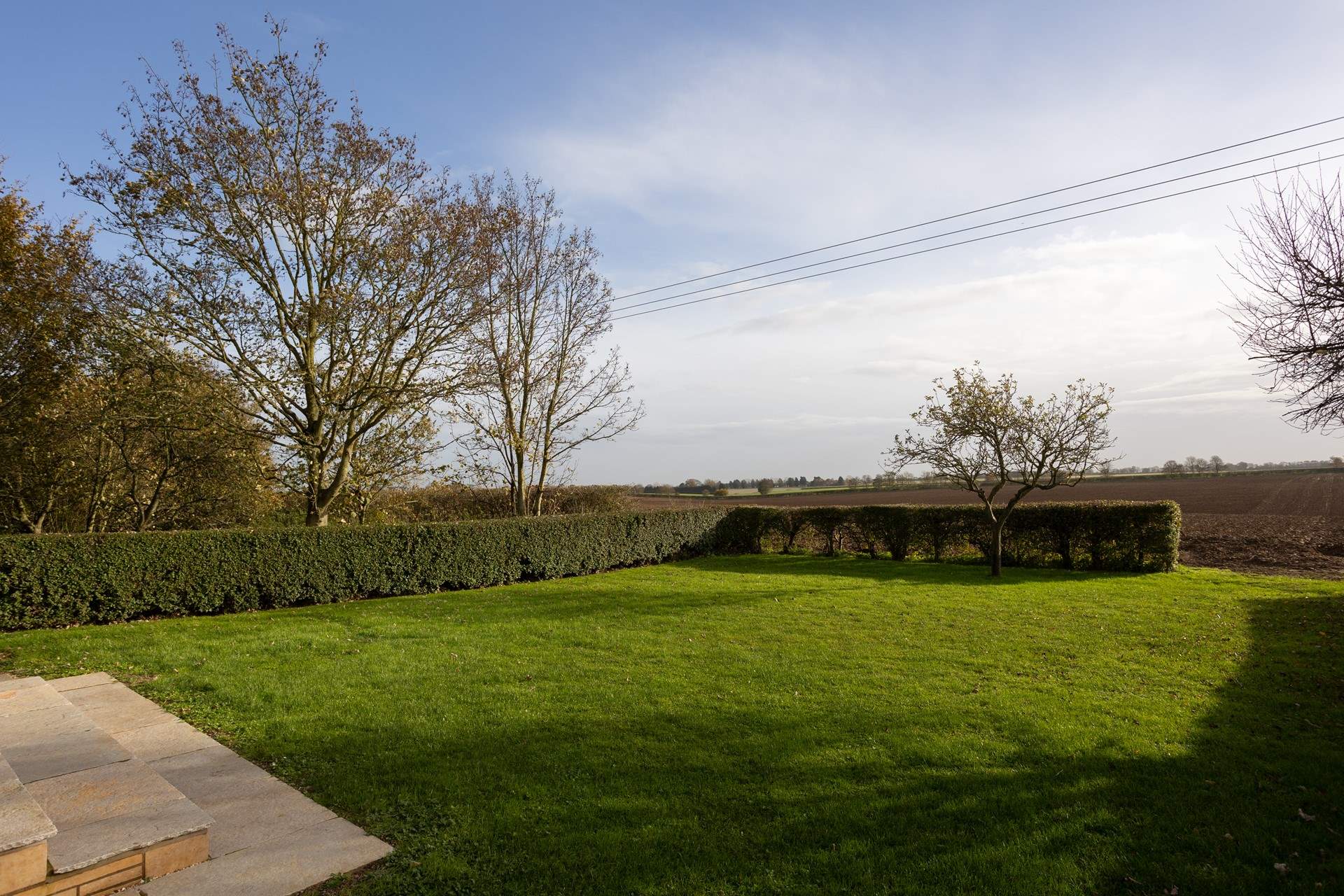 The large garden opens onto the fields beyond.