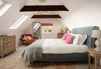 Original beams and king-size bed grace this interior designed bedroom.