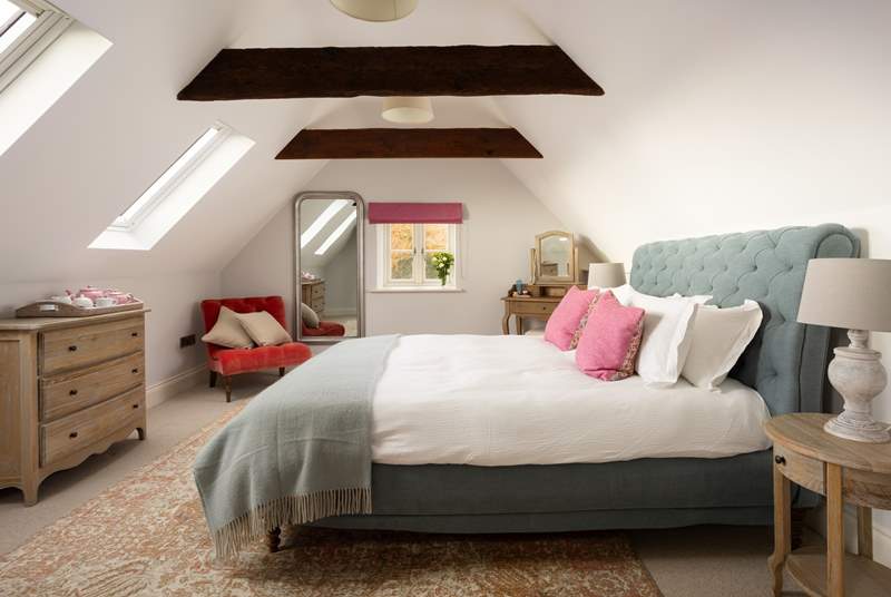 Original beams and king-size bed grace this interior designed bedroom.