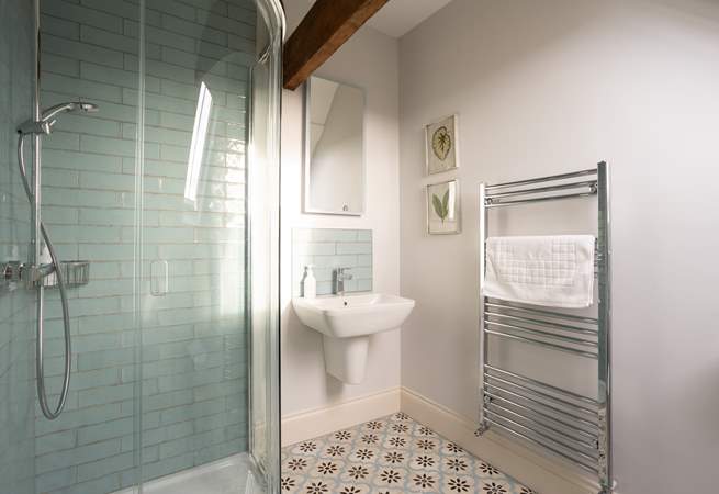 The en suite shower-room has pretty pale blue tiling and original beams. 