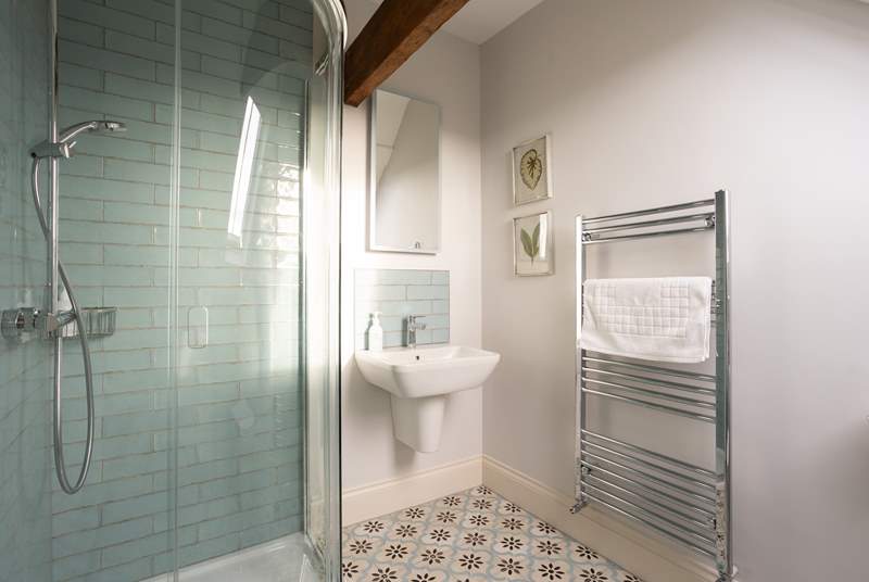 The en suite shower-room has pretty pale blue tiling and original beams. 