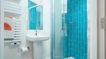 The en suite shower-room with vibrant blue tiles and a cleverly fitted skylight.