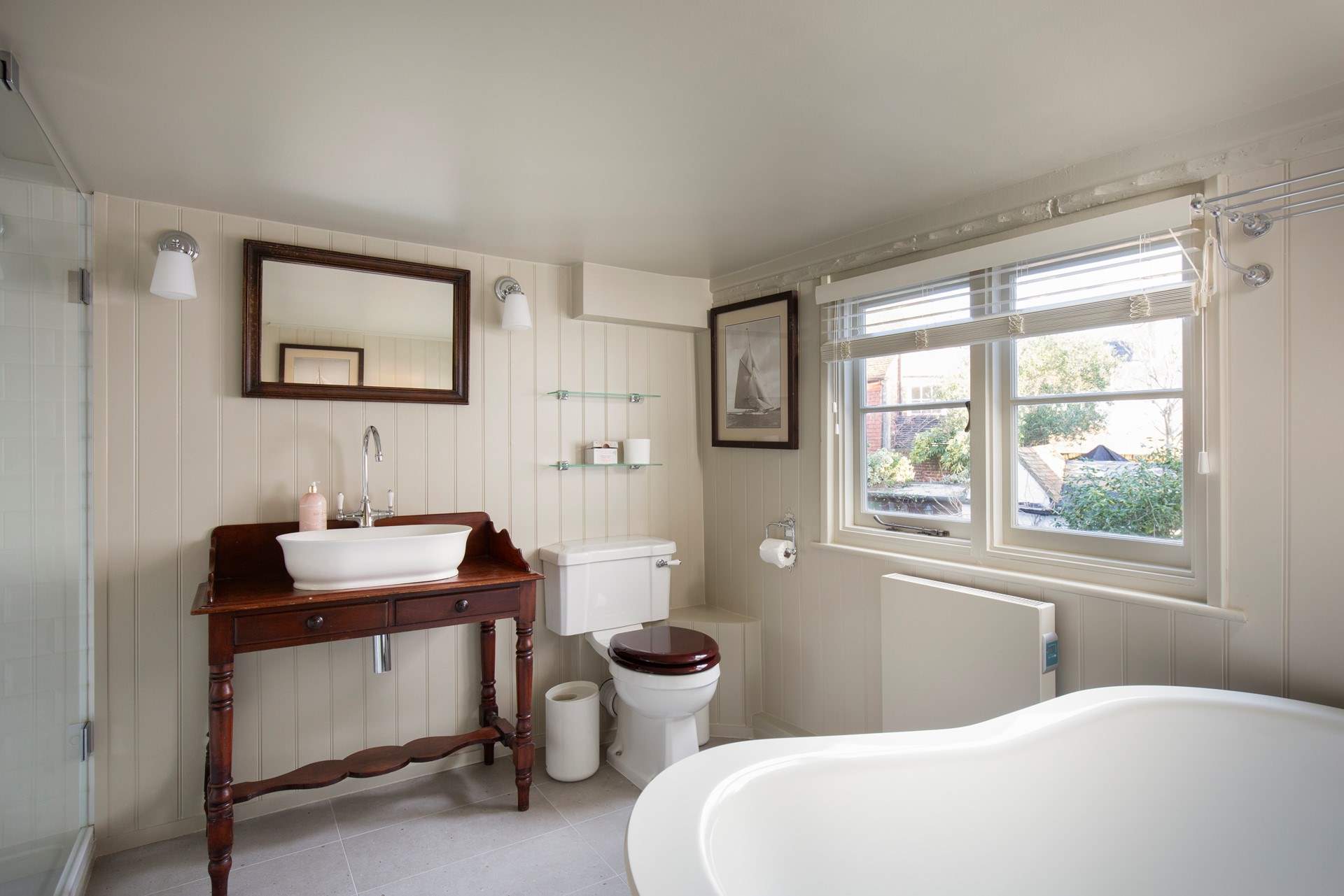 The bathroom is stylishly fitted with a shower cubicle and slipper bath.