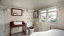 The bathroom is stylishly fitted with a shower cubicle and slipper bath.