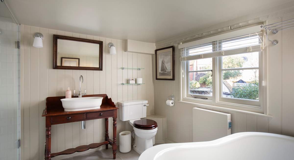 The bathroom is stylishly fitted with a shower cubicle and slipper bath.