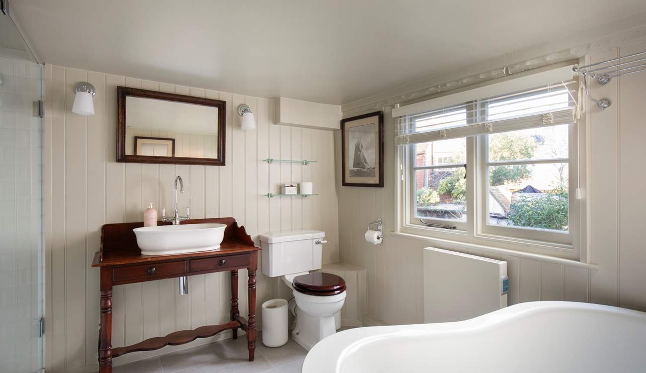 The bathroom is stylishly fitted with a shower cubicle and slipper bath.