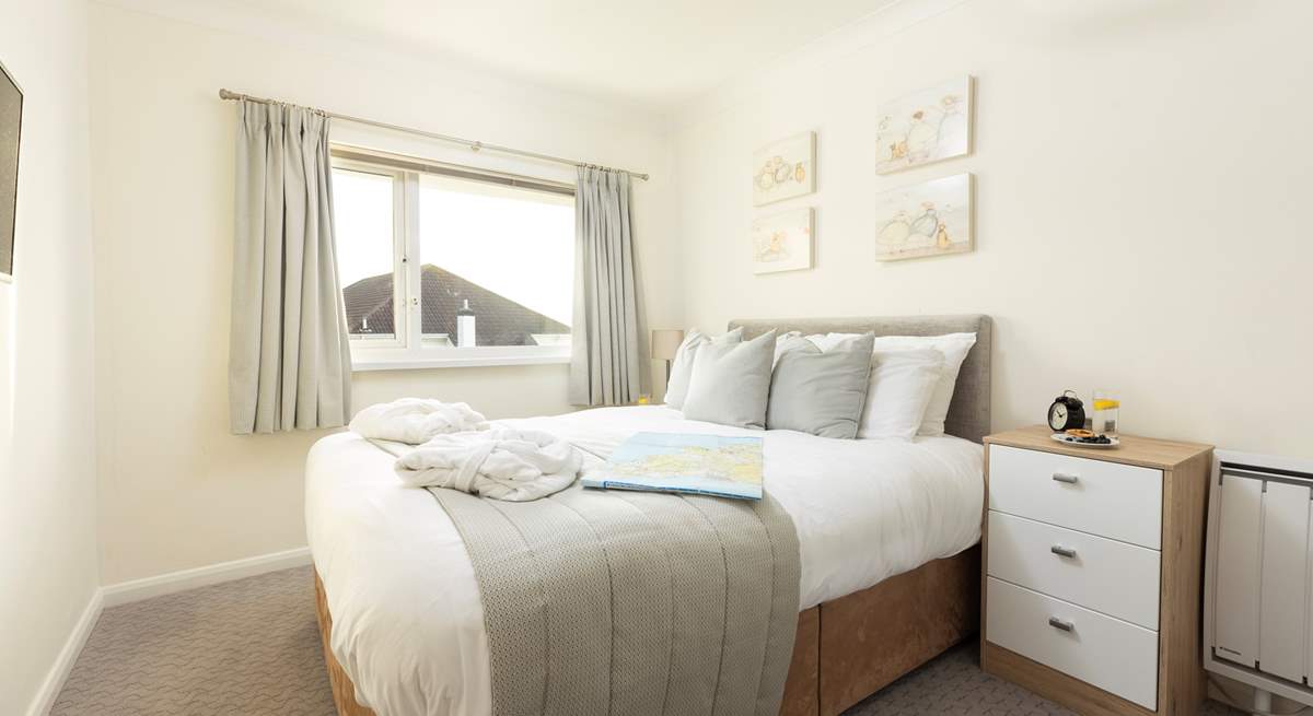 The bedroom is light and bright with calming muted tones.