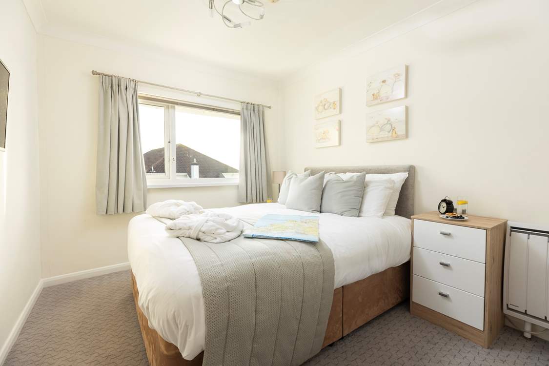 The bedroom is light and bright with calming muted tones.