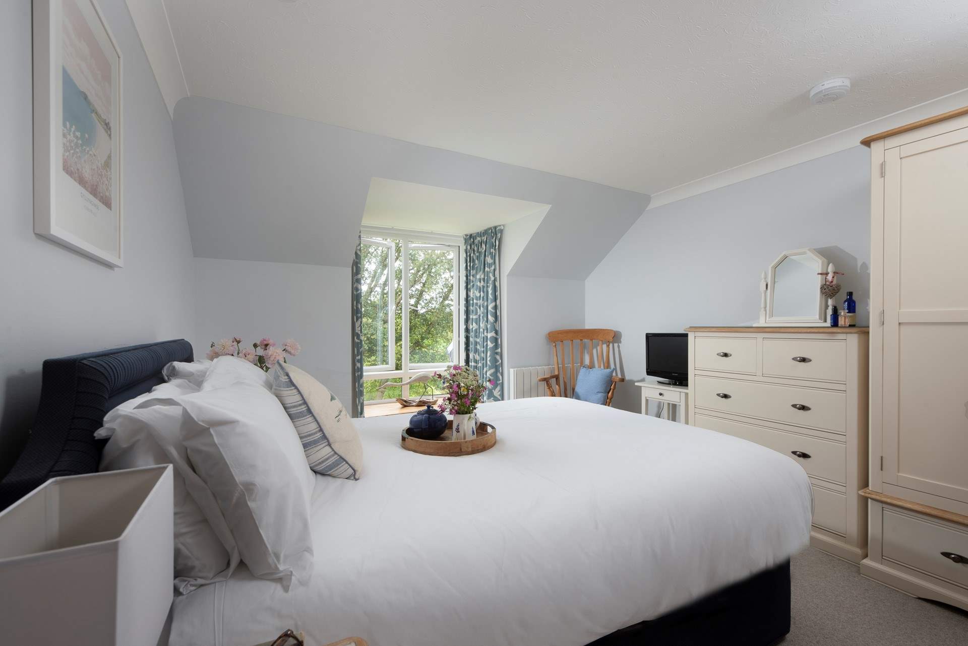 The main bedroom has a large king-size bed and views from the window out to sea. 