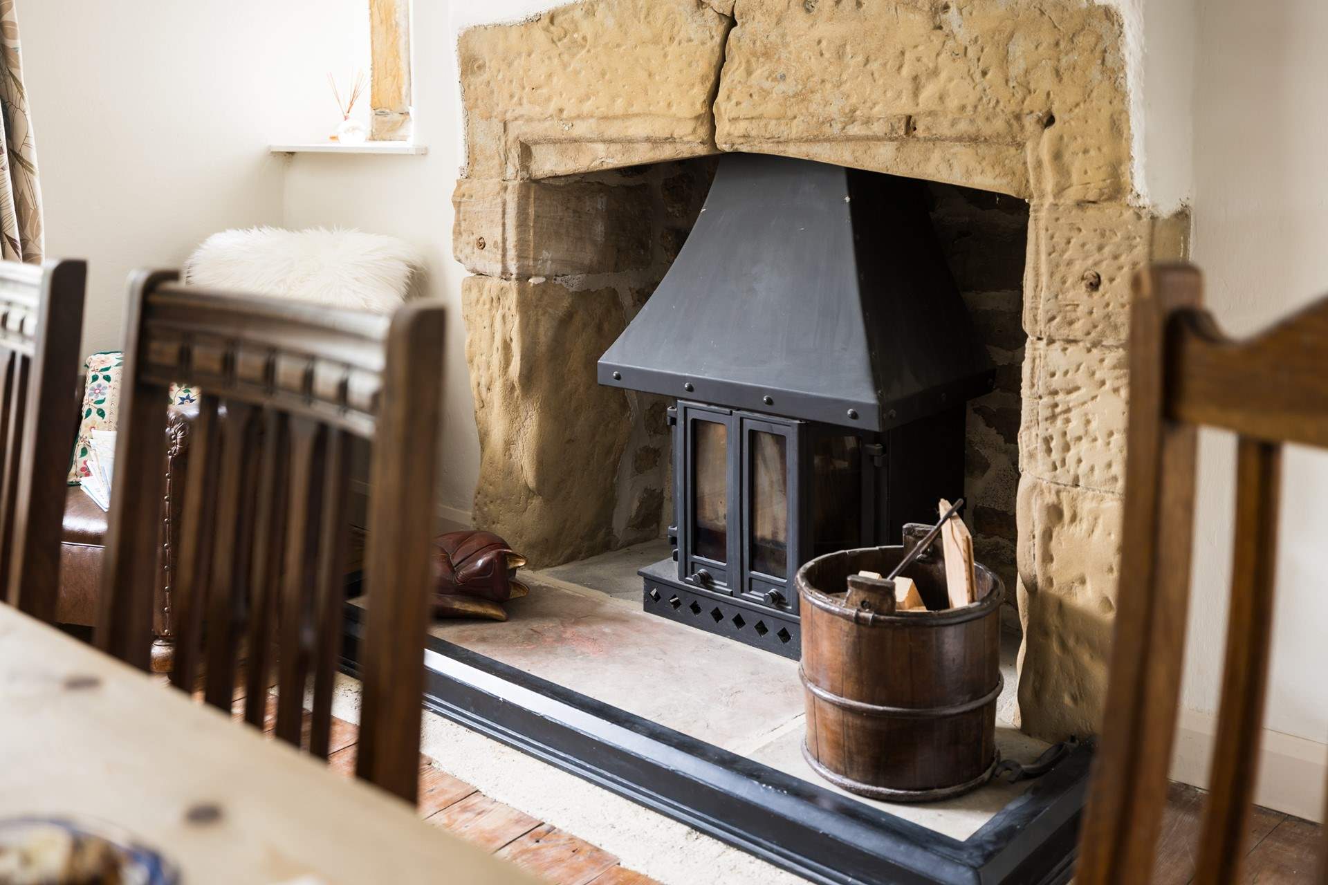 The wood-burner sits in a beautiful fireplace.