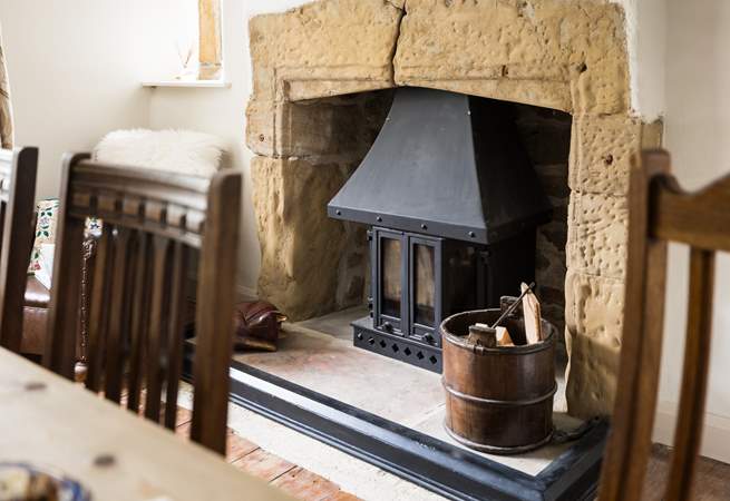 The wood-burner sits in a beautiful fireplace.