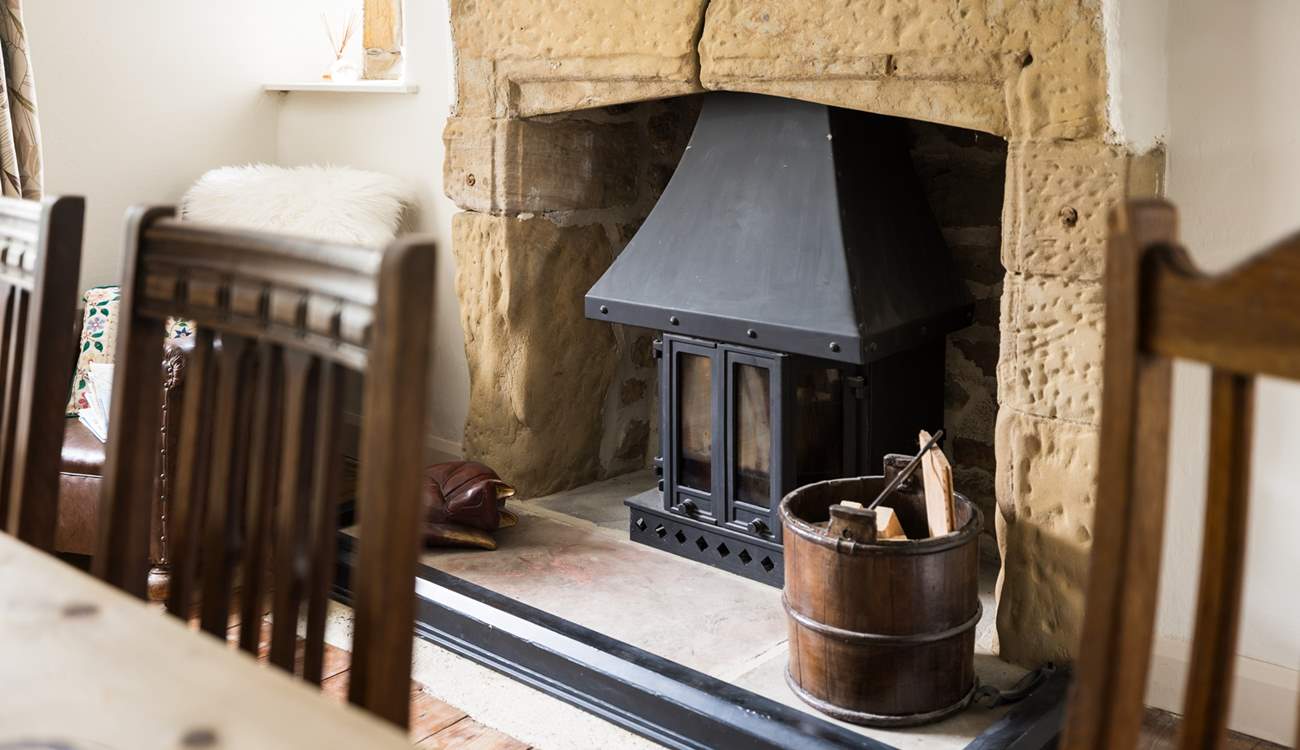 The wood-burner sits in a beautiful fireplace.