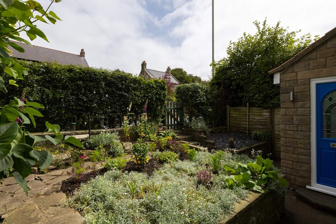 The front tiered garden is bursting with plants and flowers.