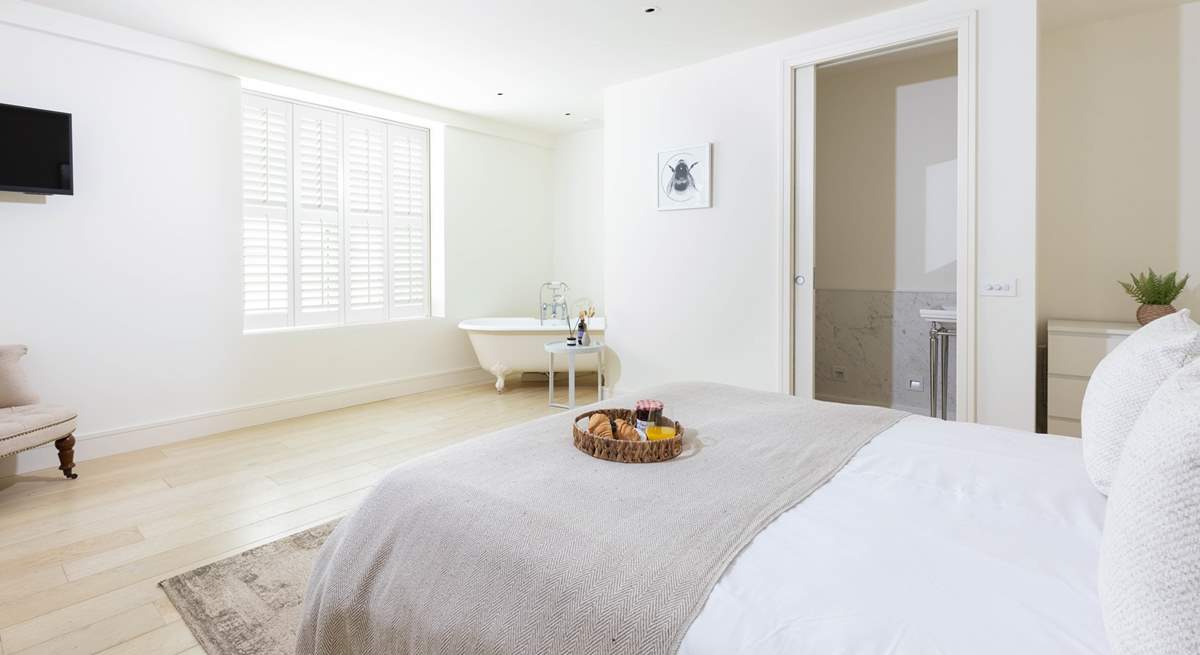 The roll-top bath adds a touch of luxury to this spacious bedroom.