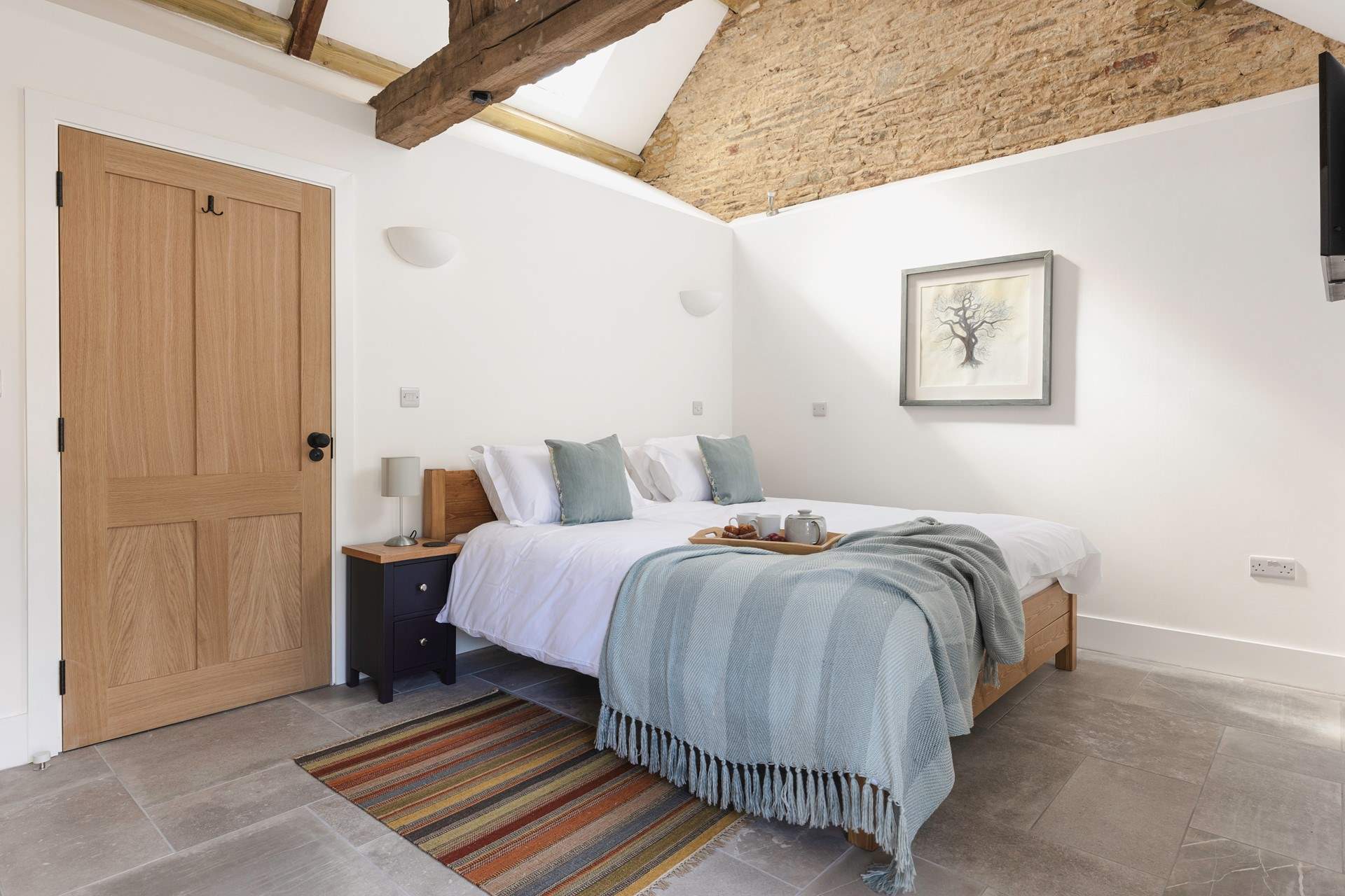 The lovely bedroom is open to the ceiling to highlight the original barn features.