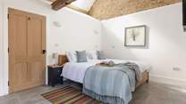 The lovely bedroom is open to the ceiling to highlight the original barn features.