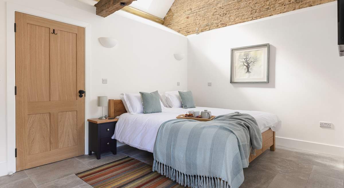 The lovely bedroom is open to the ceiling to highlight the original barn features.