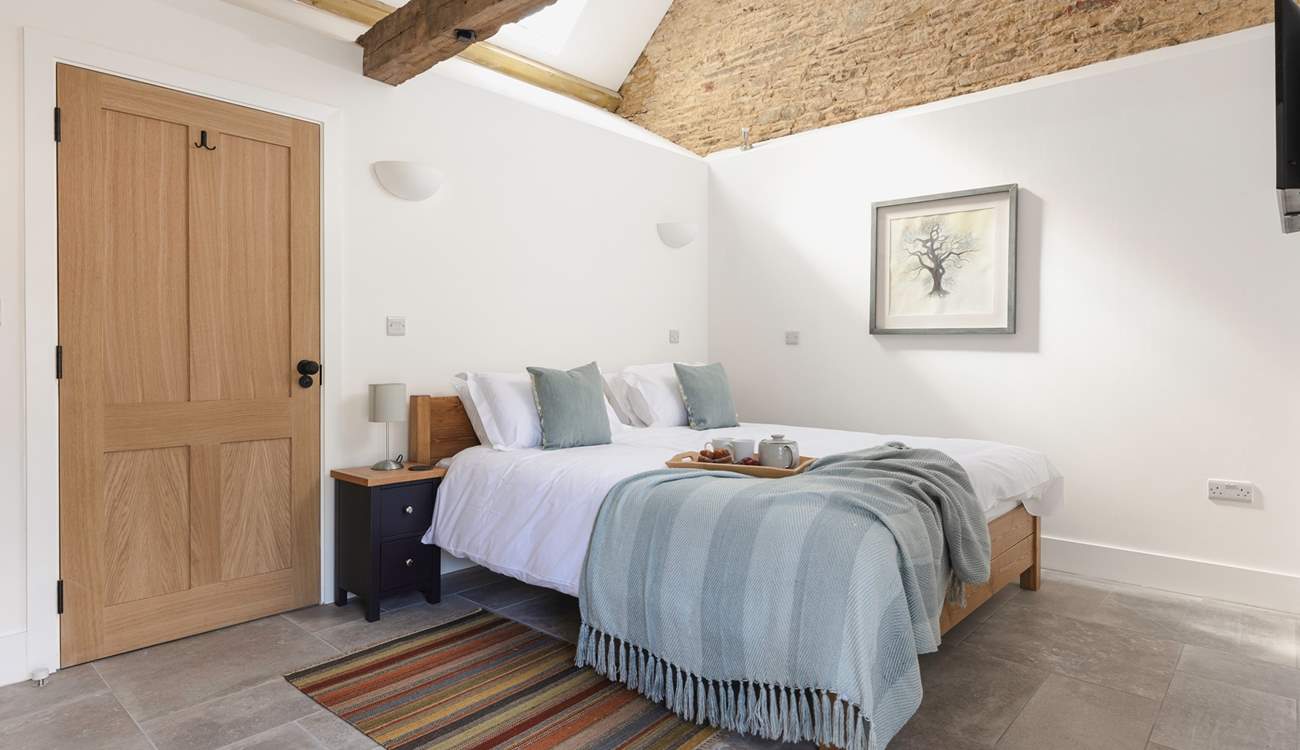 The lovely bedroom is open to the ceiling to highlight the original barn features.