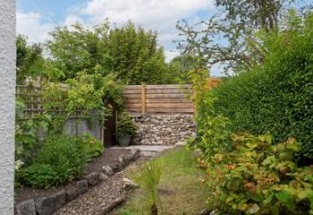 The rear garden area is a tranquil space filled with greenery. A gate leads out to a footpath which takes you down to the harbour.