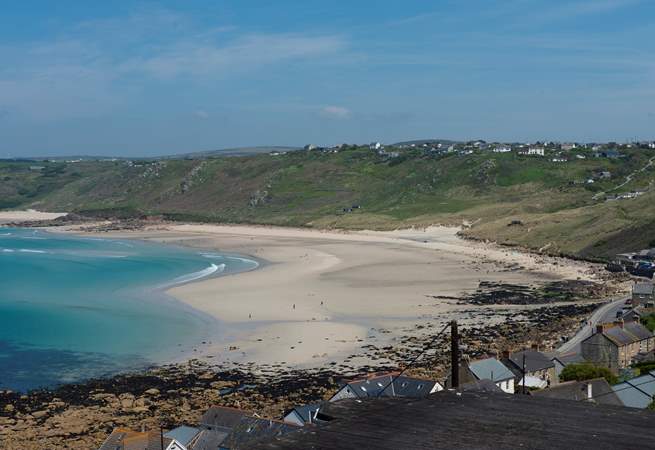 An impressive beach below, sandy shores and a bright blue sea.