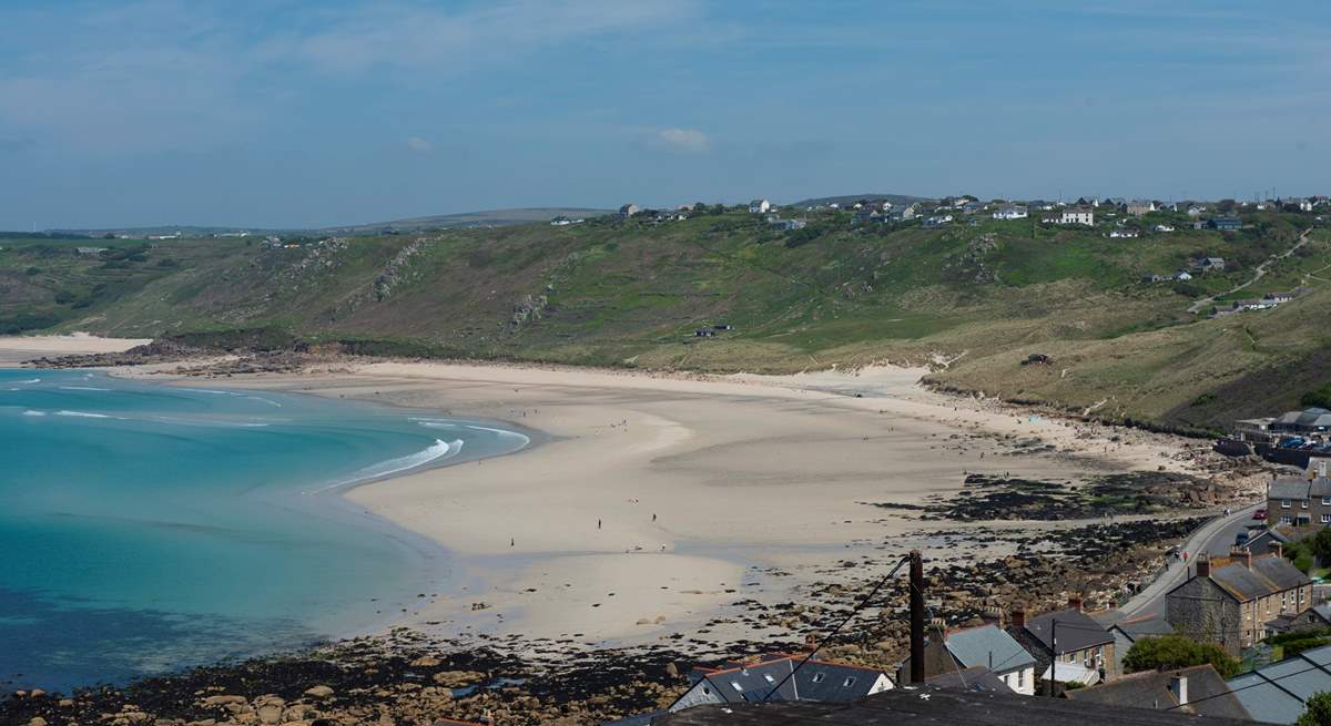 An impressive beach below, sandy shores and a bright blue sea.