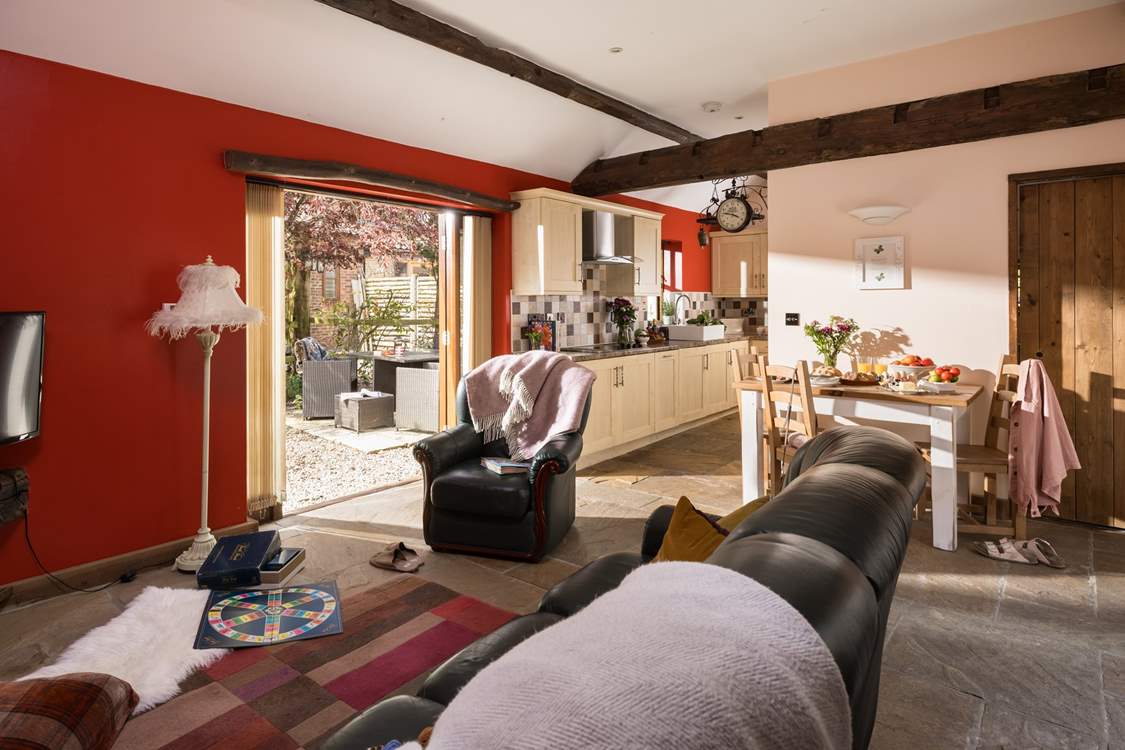 The French windows lead out to the quaint garden, which is surrounded by mature bushes and trees.