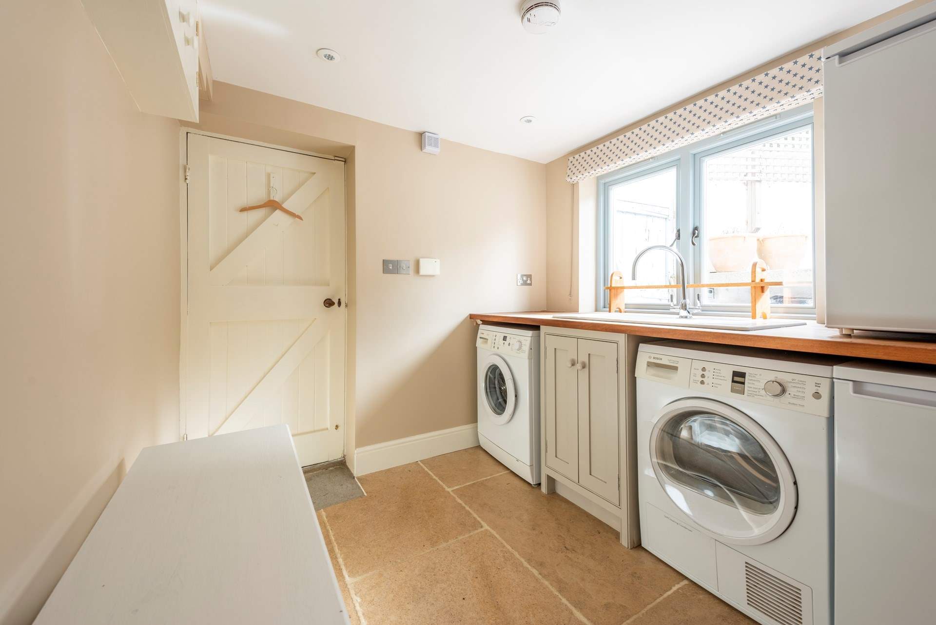The handy utility room has a freezer, washing machine, tumble drier and wash-basin. 