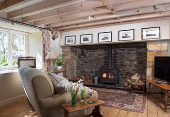 The open plan living-room with its enormous original Tudor inglenook fireplace fitted with a wood-burning stove.
