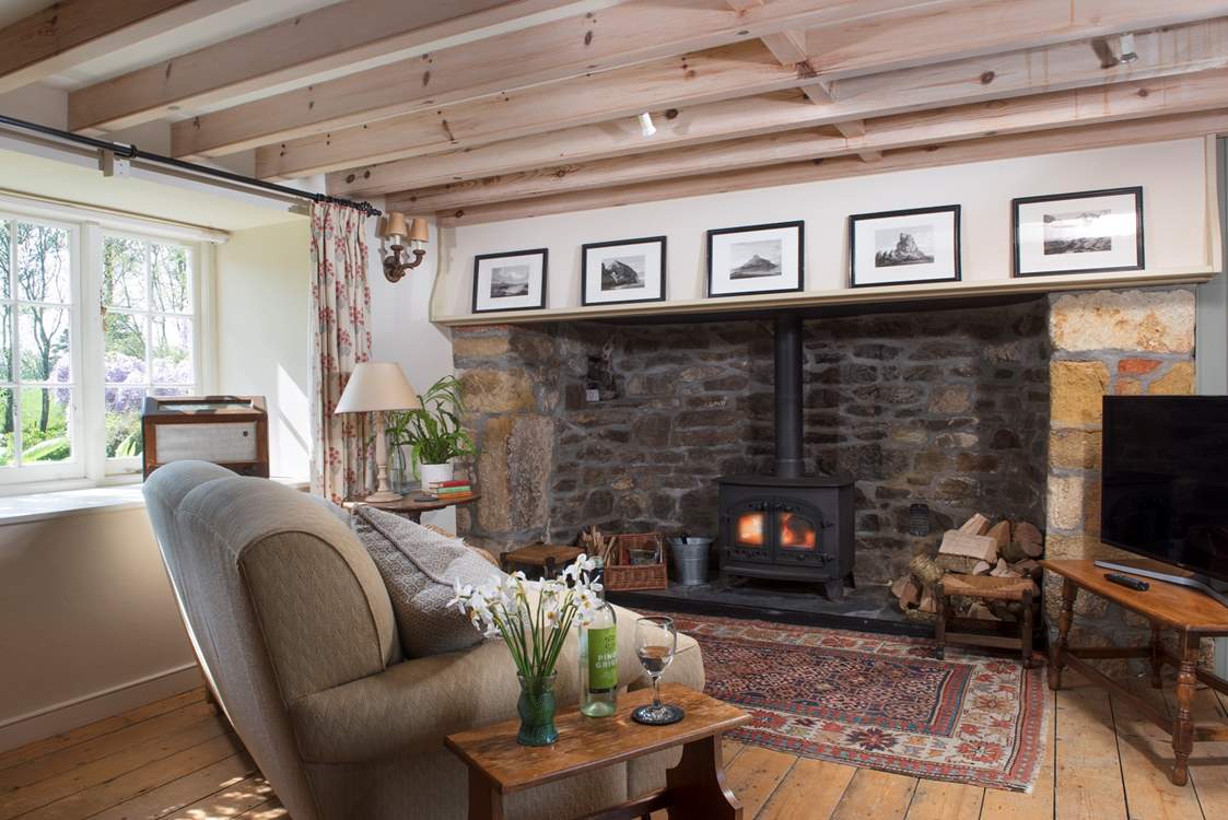 The open plan living-room with its enormous original Tudor inglenook fireplace fitted with a wood-burning stove.