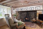 The open plan living-room with its enormous original Tudor inglenook fireplace fitted with a wood-burning stove.