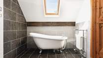 The bedroom comes complete with a delightful en suite bathroom featuring an elegant roll-top bath.