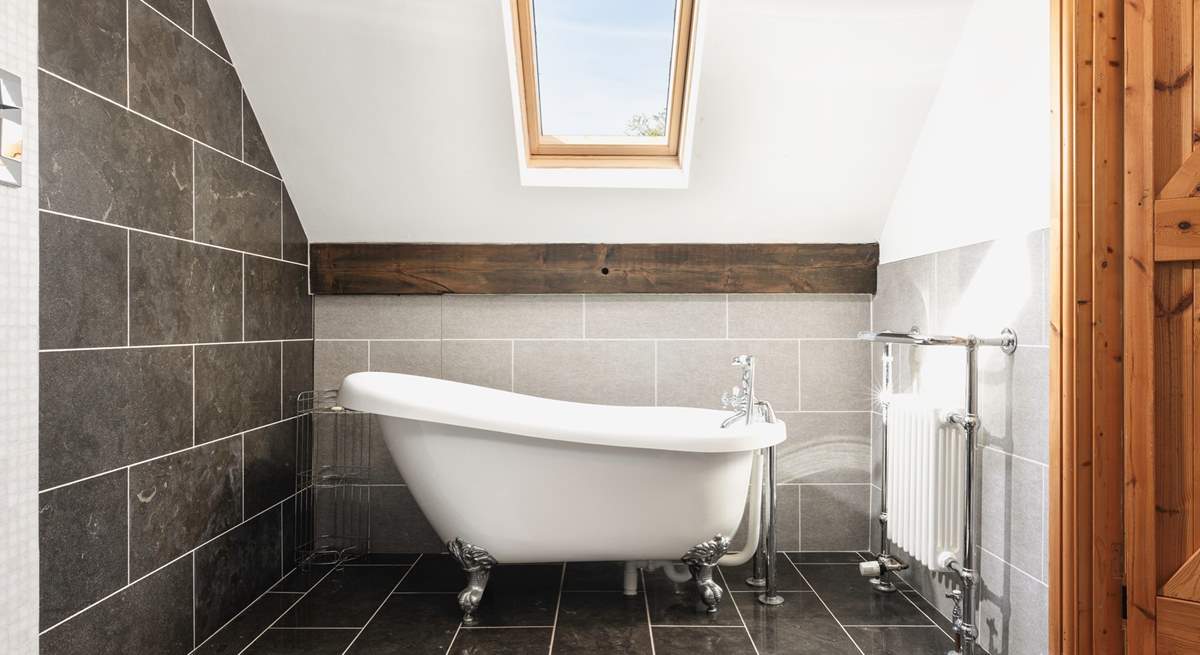 The bedroom comes complete with a delightful en suite bathroom featuring an elegant roll-top bath.