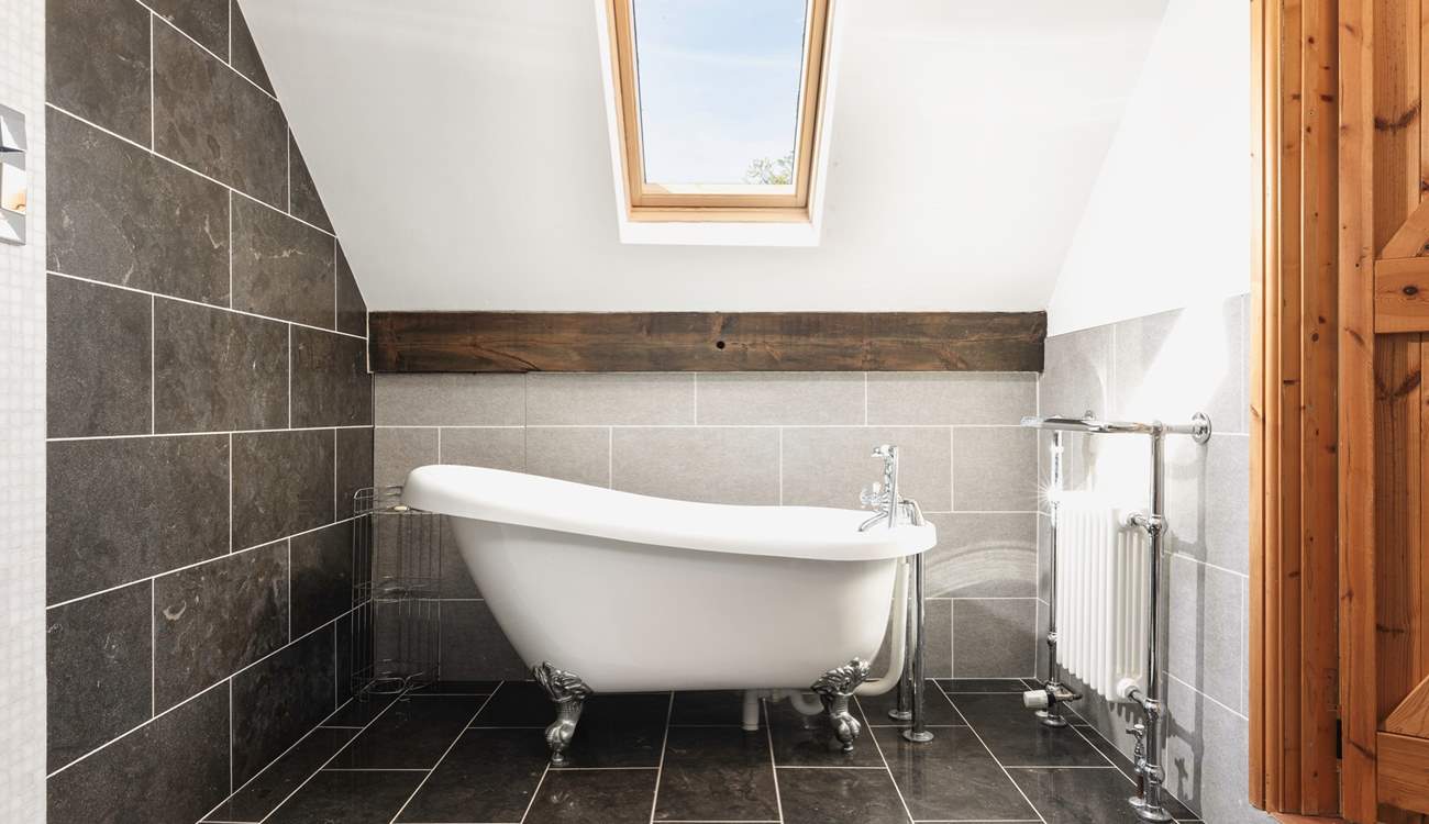 The bedroom comes complete with a delightful en suite bathroom featuring an elegant roll-top bath.