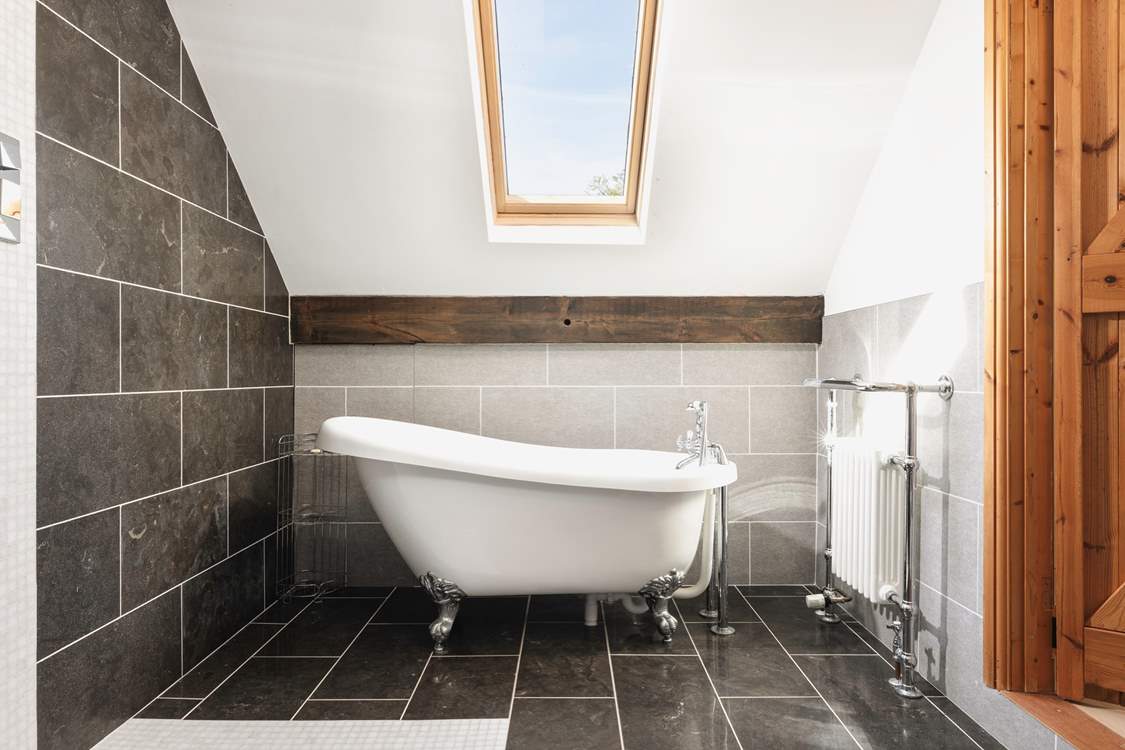 The bedroom comes complete with a delightful en suite bathroom featuring an elegant roll-top bath.