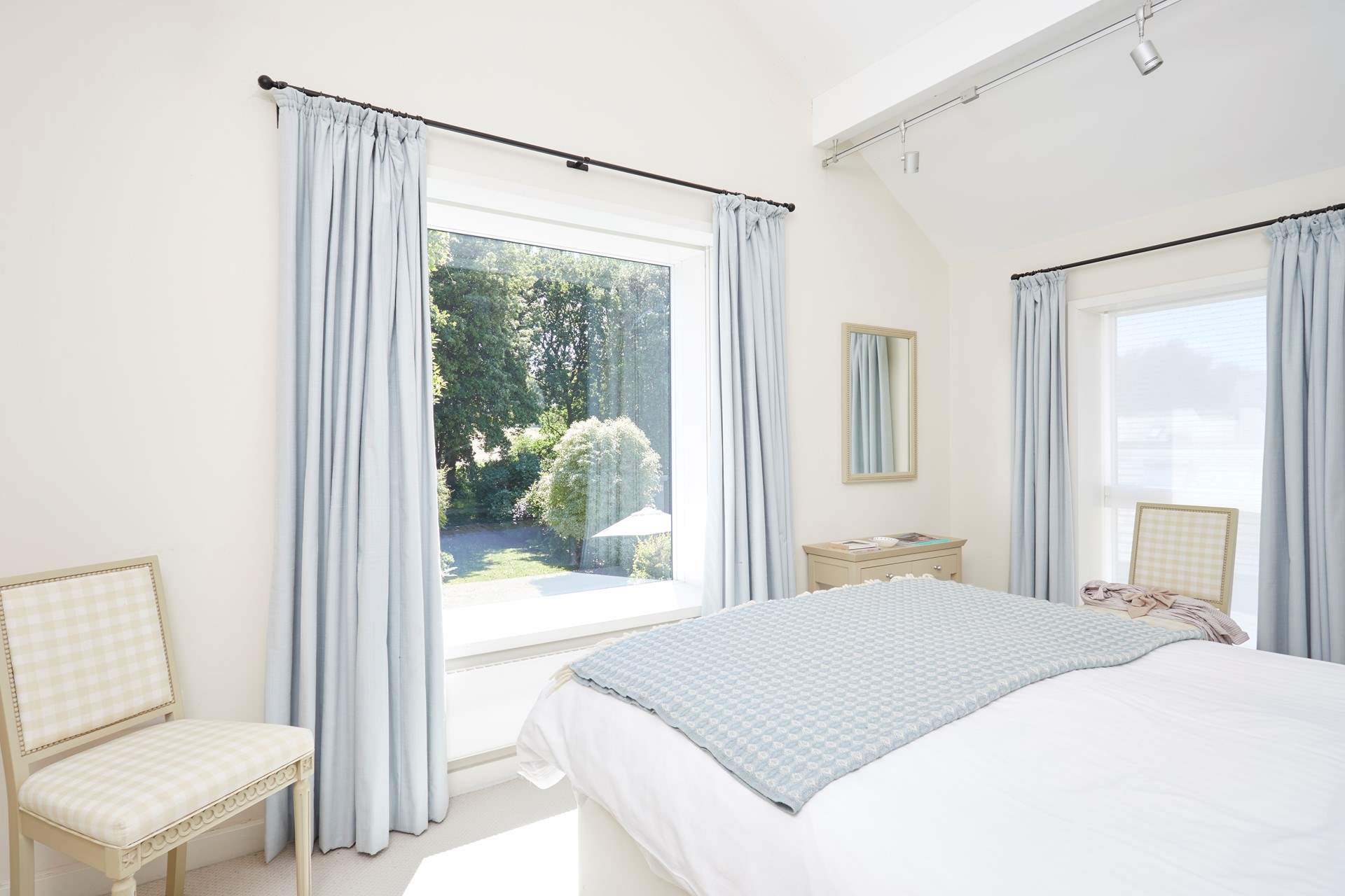 Offering views over the pretty garden, the main bedroom suite with a king-size bed dressed in crisp white linens.
