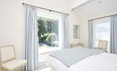 Offering views over the pretty garden, the main bedroom suite with a king-size bed dressed in crisp white linens. - Thumbnail Image