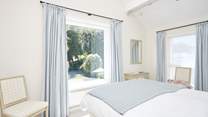 Offering views over the pretty garden, the main bedroom suite with a king-size bed dressed in crisp white linens.