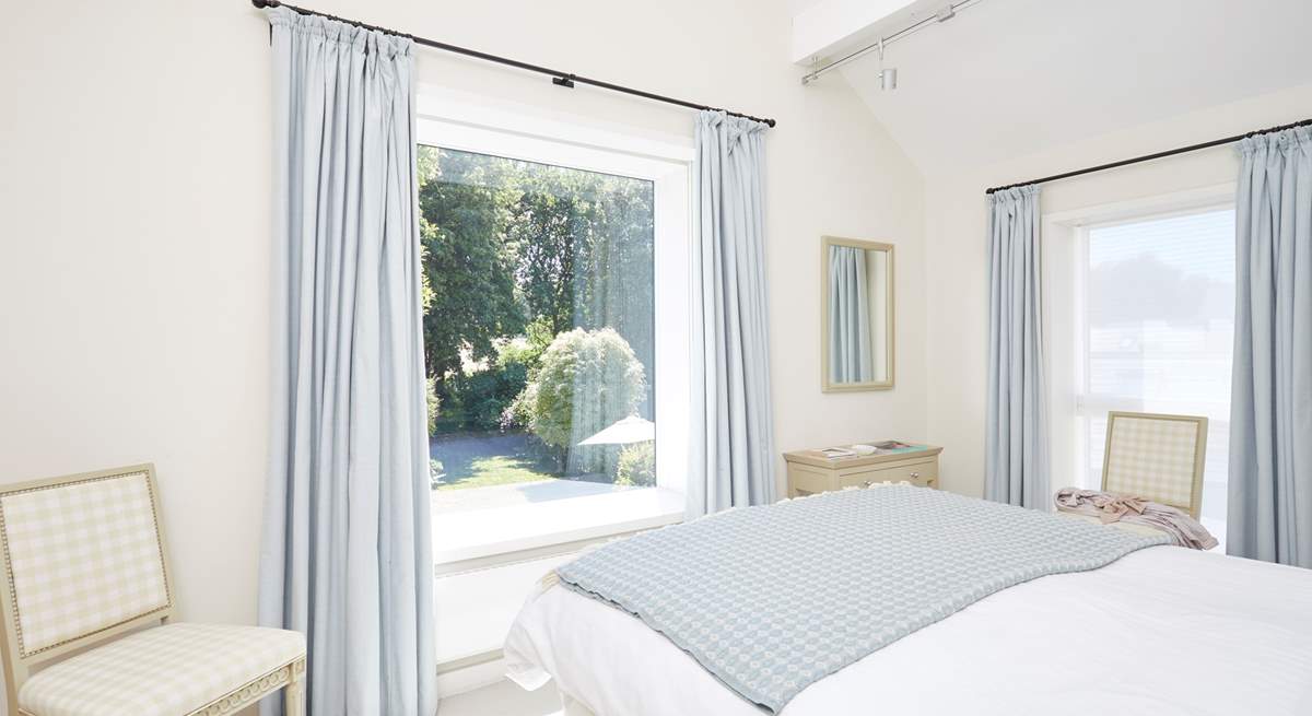 Offering views over the pretty garden, the main bedroom suite with a king-size bed dressed in crisp white linens.