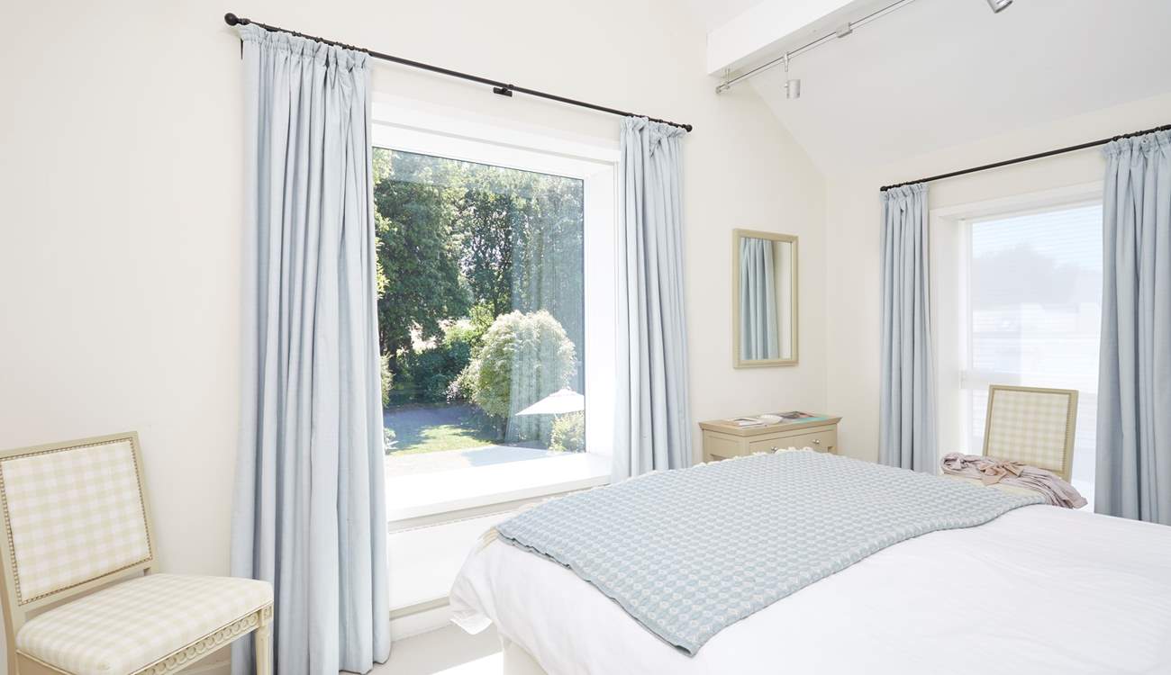 Offering views over the pretty garden, the main bedroom suite with a king-size bed dressed in crisp white linens.