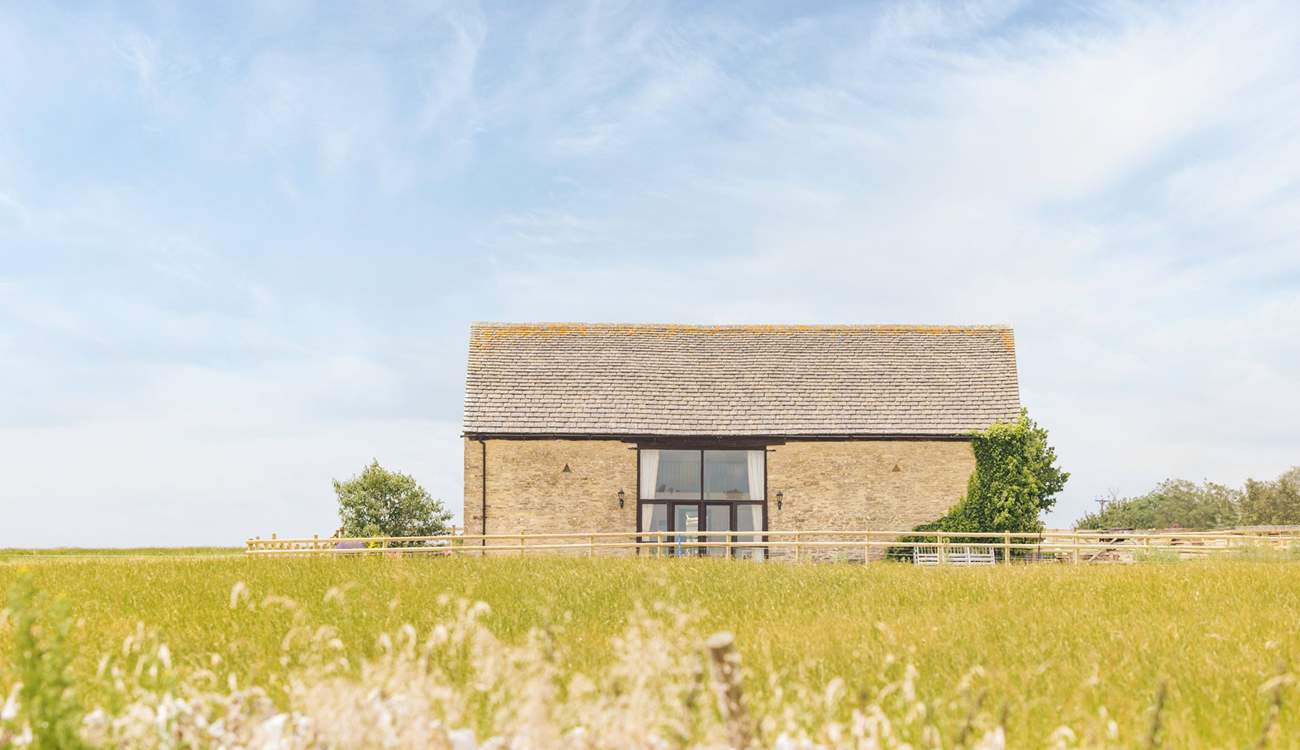 The barn appears at the end of a track, off a quiet country lane, rising slightly above the surrounding fields