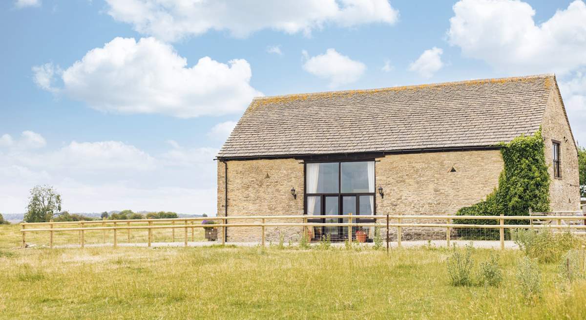 A farm fence separates the courtyard from the surrounding fields, providing unobstructed views across this rural idyll.