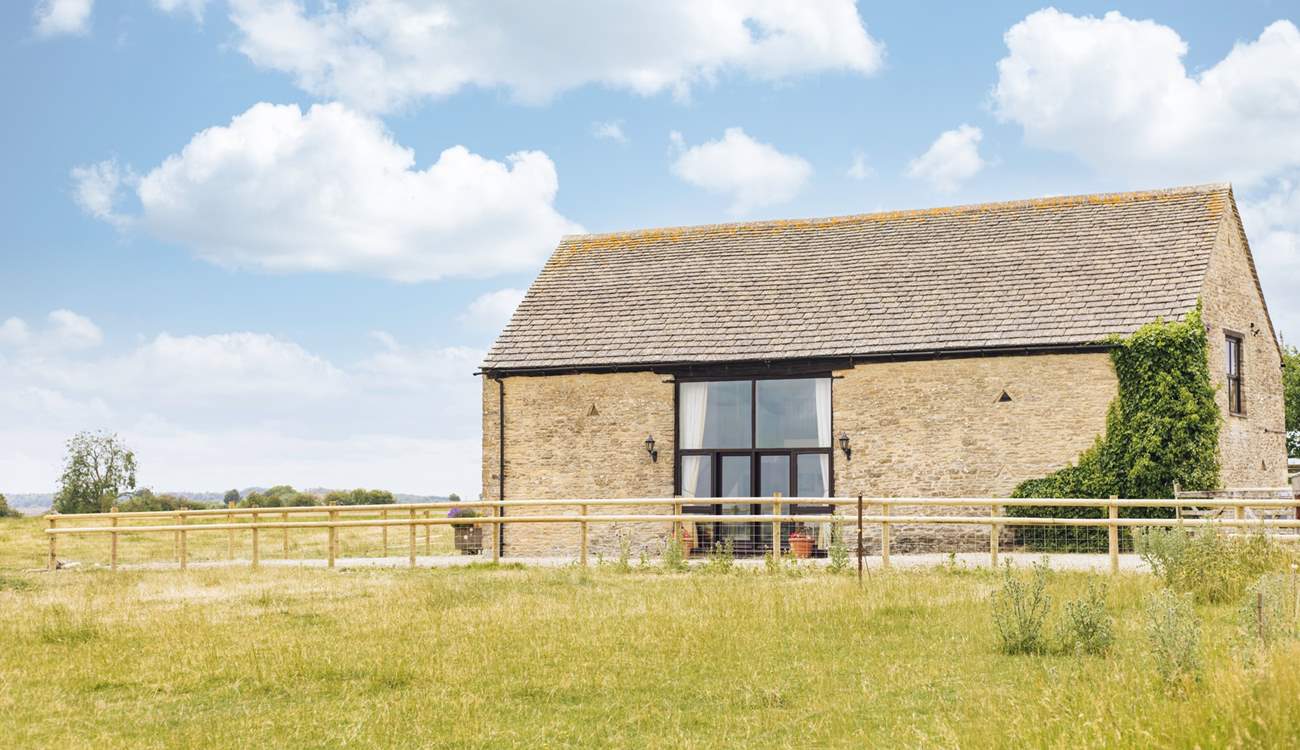 A farm fence separates the courtyard from the surrounding fields, providing unobstructed views across this rural idyll.