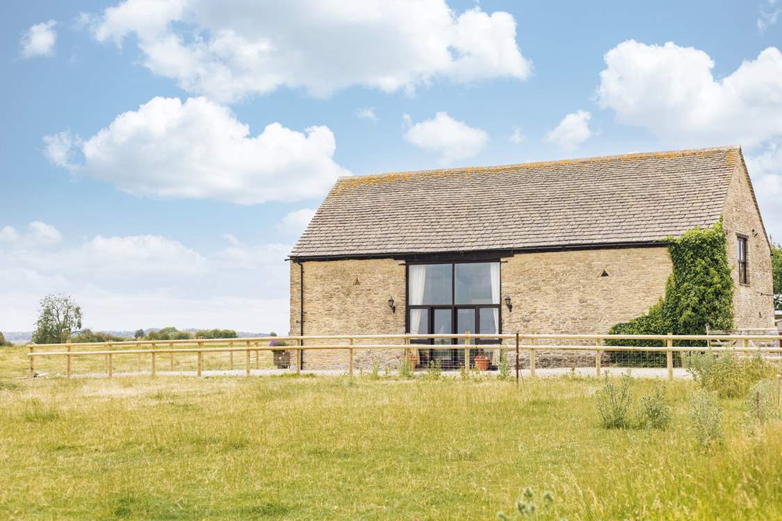 A farm fence separates the courtyard from the surrounding fields, providing unobstructed views across this rural idyll.
