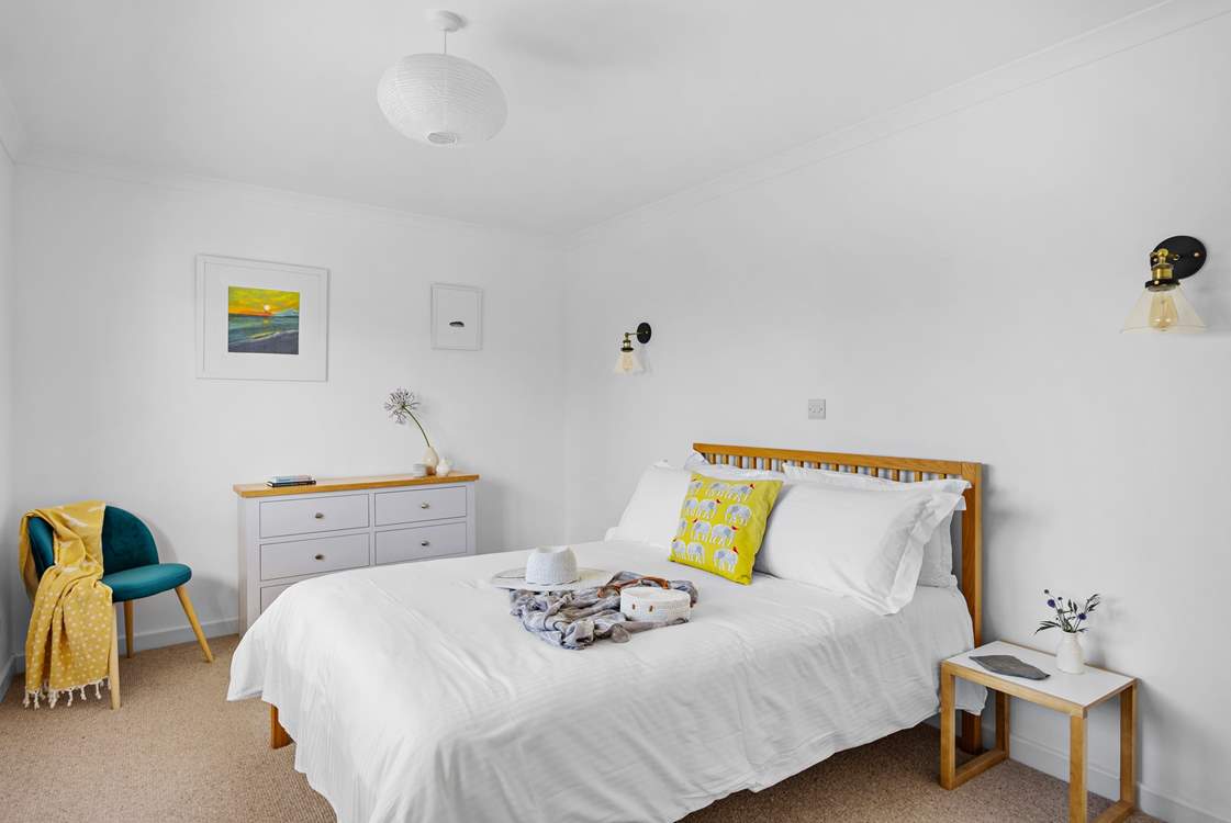 Bedroom 2 has a double bed dressed with crisp white linens, a tranquil space to rest after a day on the beach.