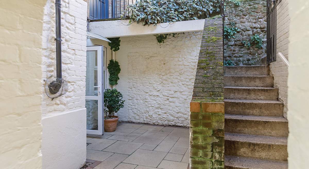 Steps lead down from the private parking area to the enclosed courtyard.