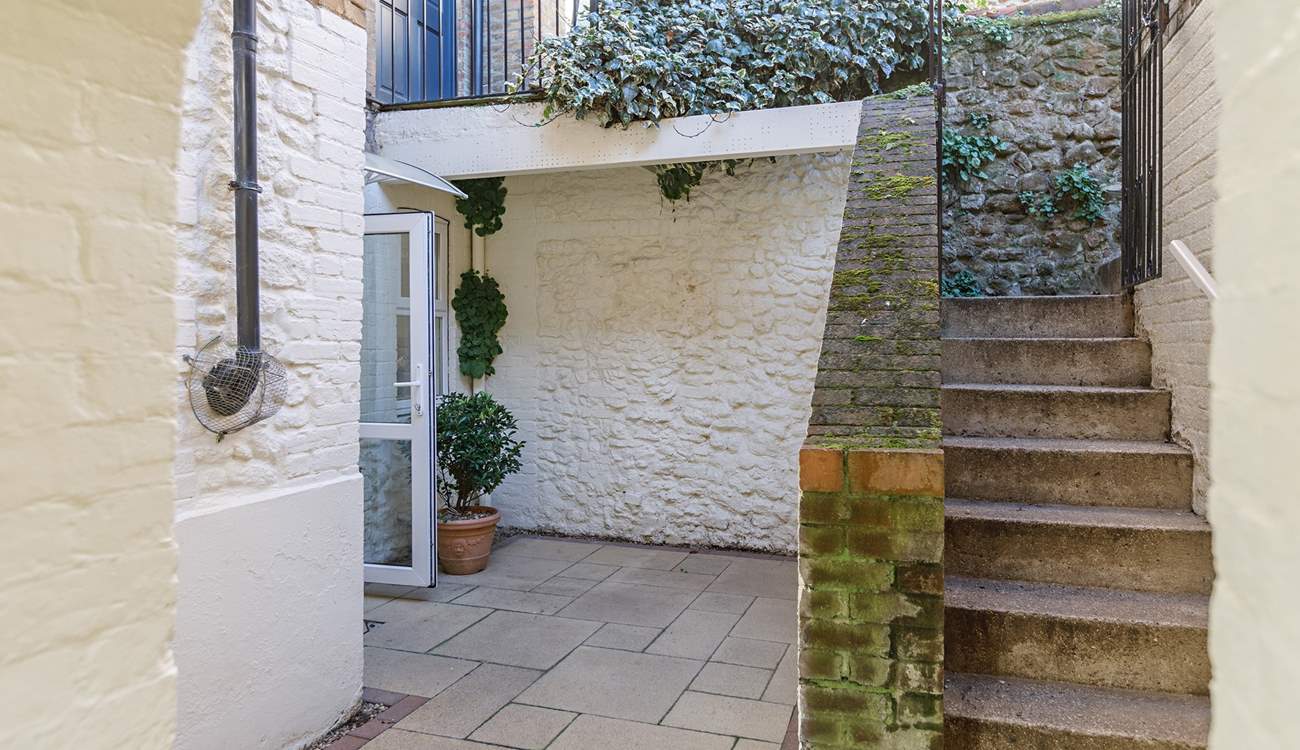 Steps lead down from the private parking-area to the enclosed courtyard.